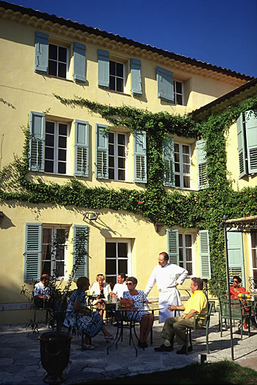 Ein idyllisch gelegenes Restaurant im Innenhof in Frankreich. Der Garçon nimmt die Bestellungen der Kunden auf