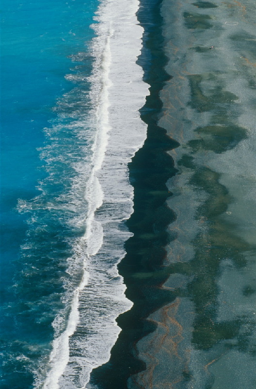 Die Wellen brechen am Strand. Beeindruckende Luftaufnahme vom Cap Corse: Dunkler Strand von Nonza auf Korsika.