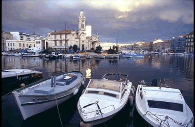 Schöne Hafenszene in Languedoc-Roussillon. Kleinere und größere Boote liegen vor Anker, im Hintergrund stehen schöne alte Häuser