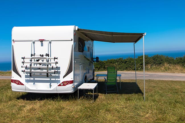 Campingwagen steht an der Klippenwand direkt am Meer