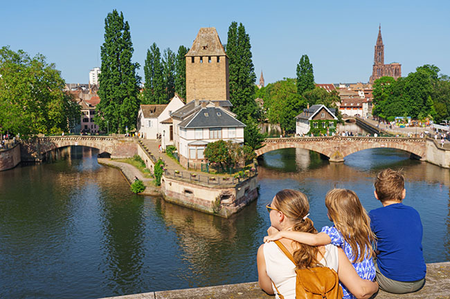 Eine Touristenfamilie blickt auf die Ponts Couverts in Straßburg, Elsass, Frankreich. Das Kanalviertel „La Petite France“ in Straßburg im Sommer
