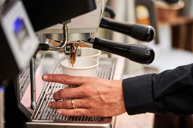Frischer Kaffee aus einem Kaffeeautomaten von einer Servicekraft gekocht