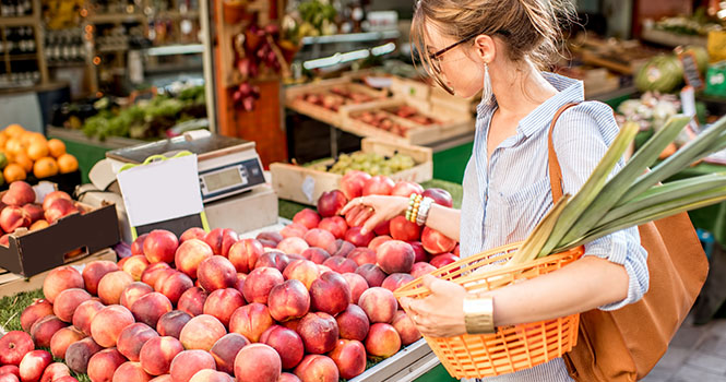 Markt in Frankreich mit frischen lokalen Produkten. Eine Frau steht vor einem Stand mit Pfirsichen