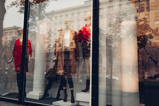 SChaufenster eines Modegeschäfts in Frankreich. Bekleidete Schaufensterpuppen in rot und beige