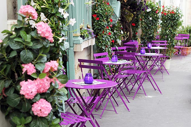 Pariser Straßencafé mit farbenfrohen Tischen.