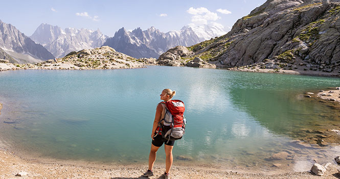 Frau beim Wandern am See in den französischen Alpen mit Blick auf den Mont Blanc. Nachhaltiger Tourismus in Frankreich